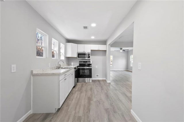 kitchen with white cabinetry, stainless steel appliances, light hardwood / wood-style flooring, and plenty of natural light