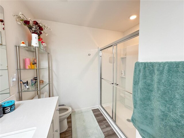 bathroom featuring hardwood / wood-style flooring, vanity, toilet, and a shower with shower door