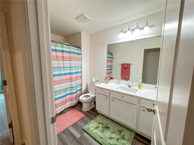 bathroom featuring hardwood / wood-style floors, vanity, a shower with shower curtain, and toilet