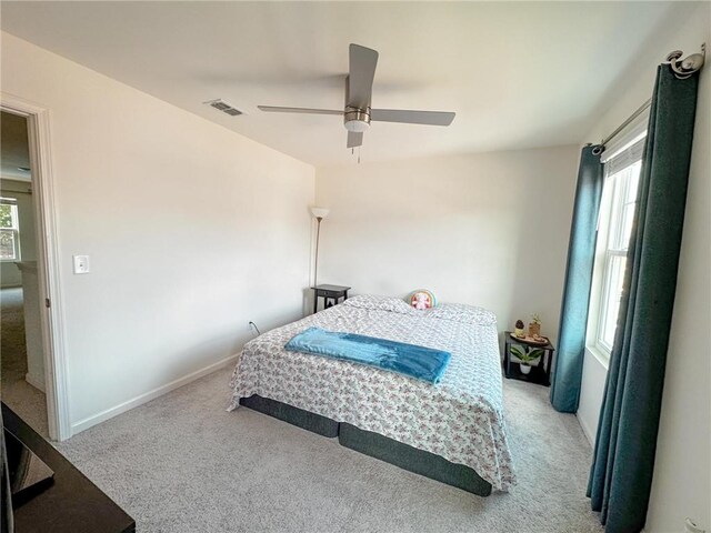 bedroom featuring multiple windows, ceiling fan, and light carpet