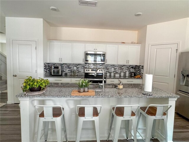 kitchen featuring white cabinets, appliances with stainless steel finishes, and light stone countertops