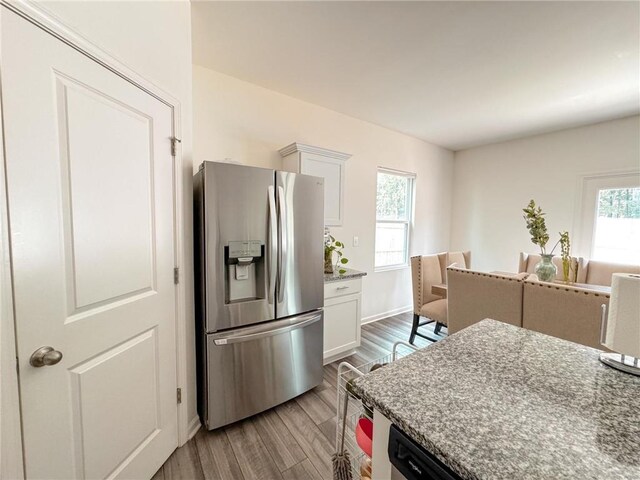 kitchen featuring light stone countertops, stainless steel fridge with ice dispenser, light hardwood / wood-style flooring, and white cabinetry