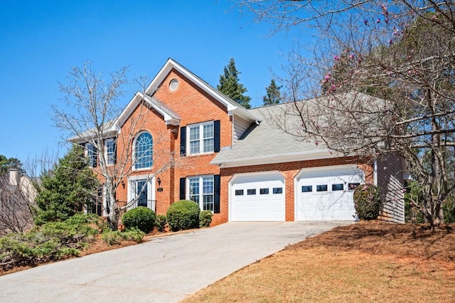 colonial house with concrete driveway, an attached garage, and brick siding