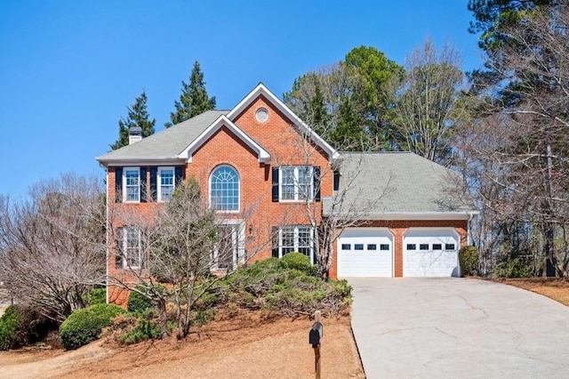 colonial inspired home with brick siding, driveway, a chimney, and a garage