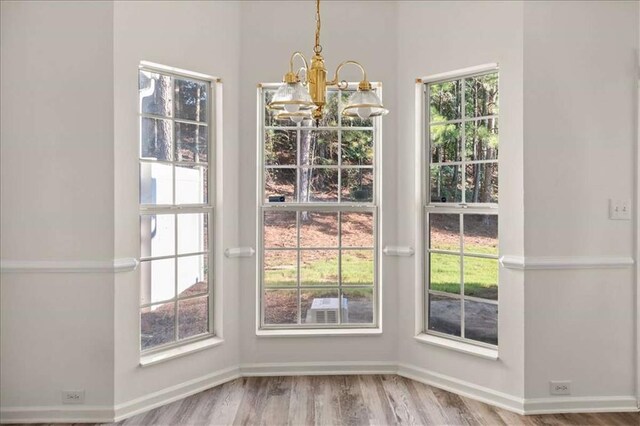 2736 Parkway Trl, Lithonia, GA 30058 - unfurnished dining area with a chandelier, wood finished floors, and baseboards