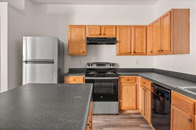 2736 Parkway Trl, Lithonia, GA 30058 - kitchen featuring stainless steel appliances, under cabinet range hood, dark countertops, and light wood-style flooring