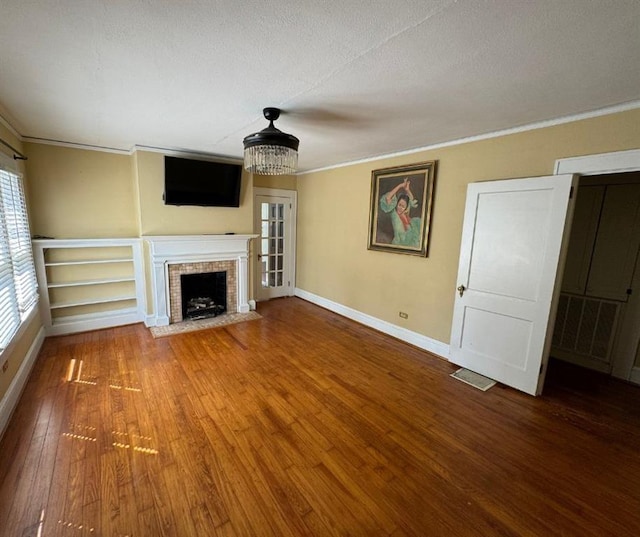 unfurnished living room with a fireplace, hardwood / wood-style floors, a textured ceiling, and ornamental molding