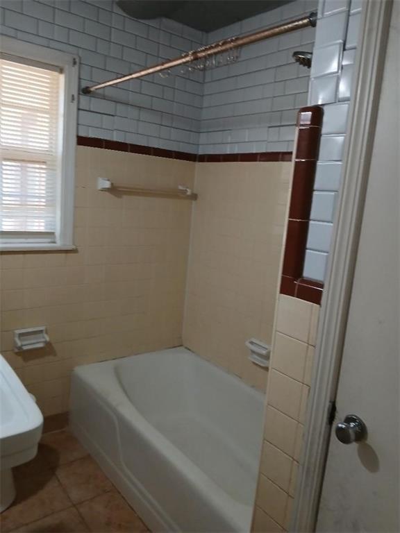 bathroom with tiled shower / bath combo, tile walls, and tile patterned floors