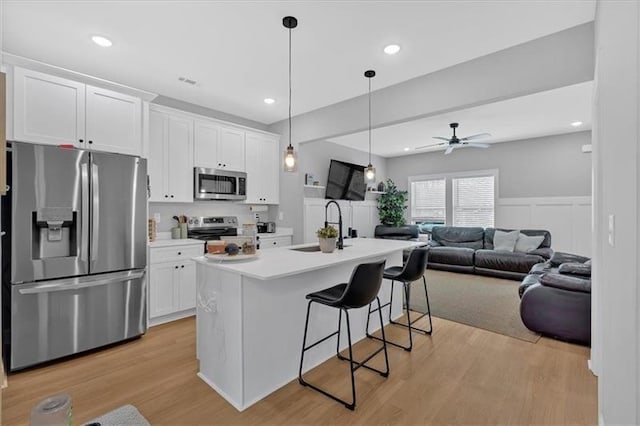 40 Crayton St, Rockmart, GA 30153 - kitchen with appliances with stainless steel finishes, a breakfast bar area, white cabinets, open floor plan, and light wood-style flooring