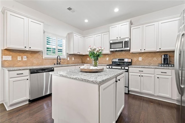 5285 Winflow Way, Suwanee, GA 30024 - kitchen featuring appliances with stainless steel finishes, a sink, dark wood-style floors, a kitchen island, and white cabinetry