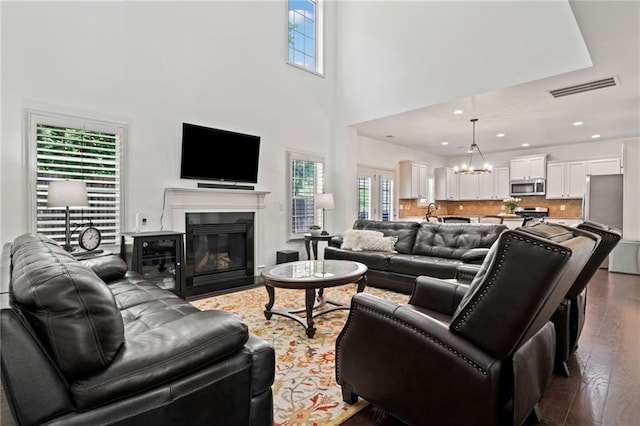 5285 Winflow Way, Suwanee, GA 30024 - living area featuring wood finished floors, a chandelier, a fireplace with flush hearth, recessed lighting, and a high ceiling