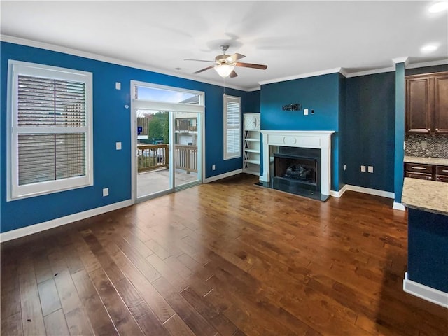 unfurnished living room with ceiling fan, dark wood-type flooring, a fireplace, baseboards, and crown molding