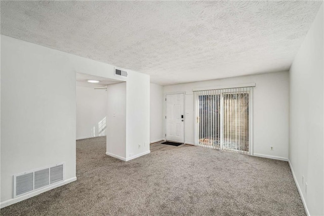 carpeted spare room with baseboards and a textured ceiling