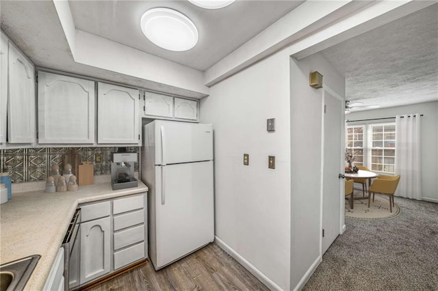 kitchen with freestanding refrigerator, light countertops, and backsplash
