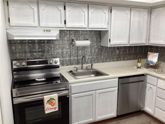 307 Adair St Unit 7-E, Decatur, GA 30030 - kitchen with stainless steel appliances, wall chimney range hood, a sink, white cabinetry, and light countertops