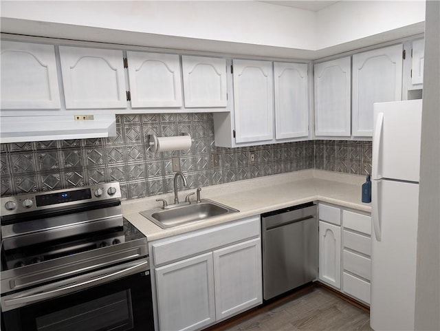 kitchen with appliances with stainless steel finishes, custom exhaust hood, a sink, light countertops, and white cabinets