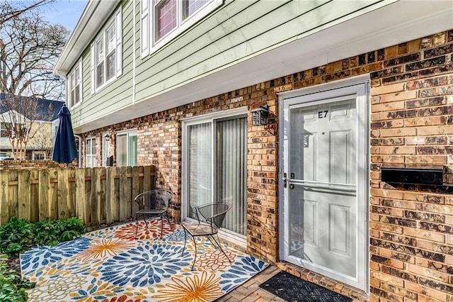 property entrance with fence and brick siding