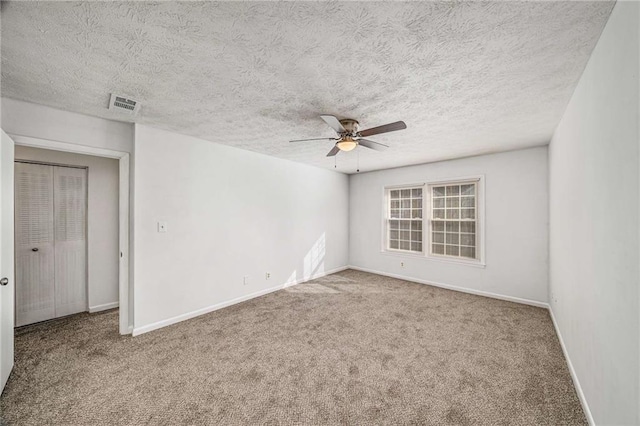 unfurnished room with a ceiling fan, carpet floors, baseboards, and a textured ceiling