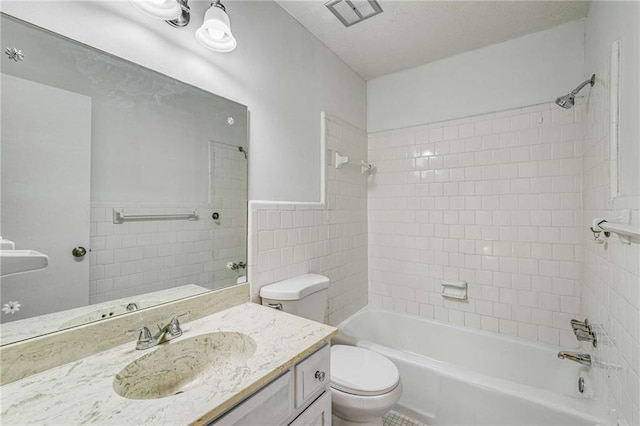 bathroom with toilet,  shower combination, tile walls, and vanity