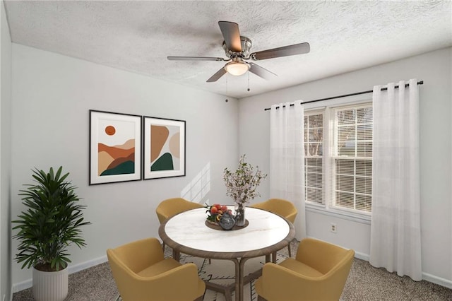 dining space featuring light colored carpet, baseboards, a ceiling fan, plenty of natural light, and a textured ceiling