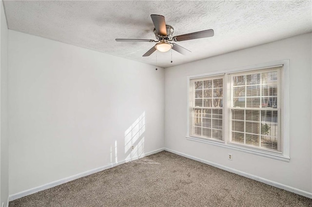 empty room with carpet, baseboards, and a textured ceiling