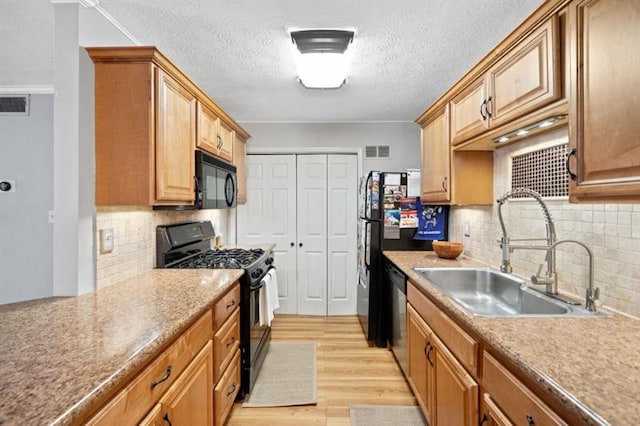 kitchen featuring sink, backsplash, light wood-type flooring, black appliances, and ornamental molding