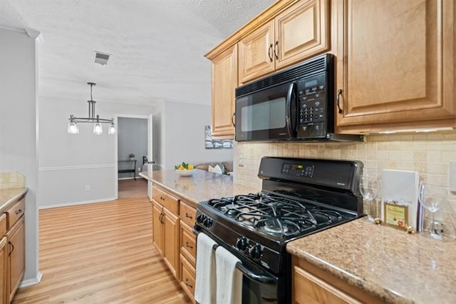 kitchen featuring backsplash, black appliances, hanging light fixtures, light hardwood / wood-style flooring, and light stone counters