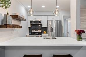 kitchen featuring kitchen peninsula, a breakfast bar area, stainless steel appliances, and white cabinets