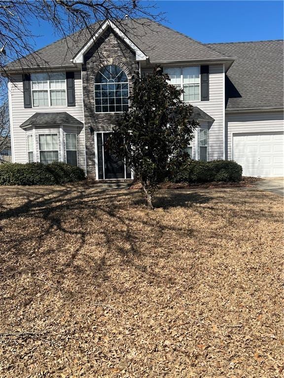 view of front of home with a garage, a front yard, roof with shingles, and driveway