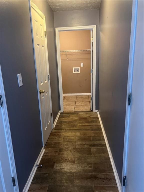 hall with a textured ceiling, baseboards, and wood finished floors