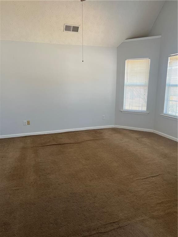 empty room with dark colored carpet, visible vents, vaulted ceiling, a textured ceiling, and baseboards