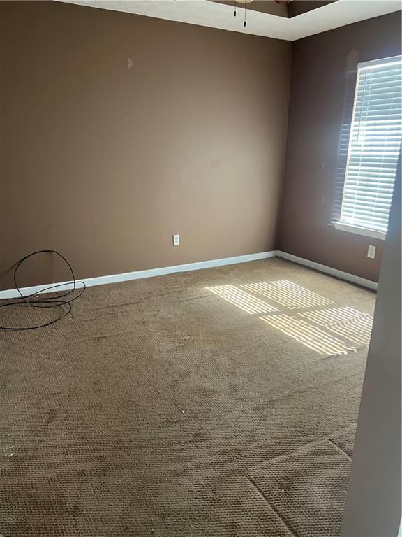 unfurnished room featuring carpet flooring, ceiling fan, and baseboards