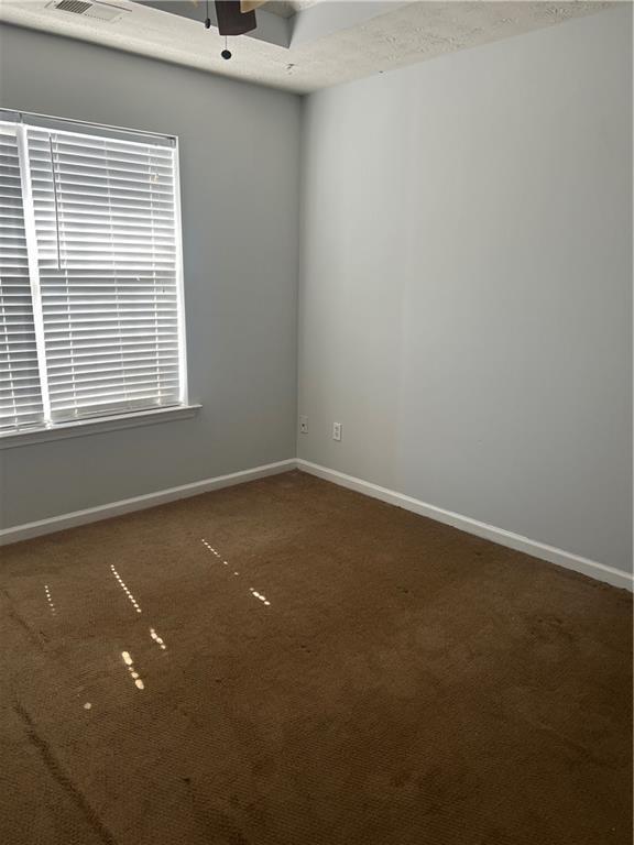 carpeted empty room with visible vents and baseboards