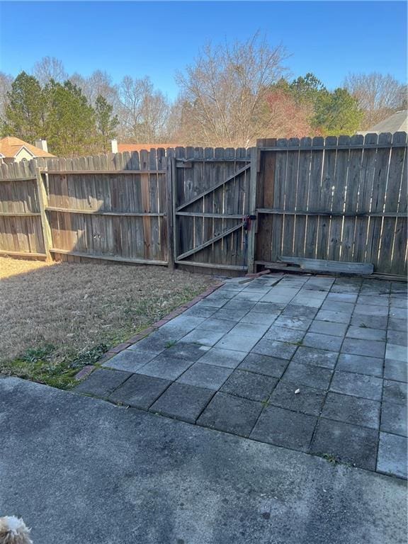 exterior space featuring a patio area, fence, and a gate