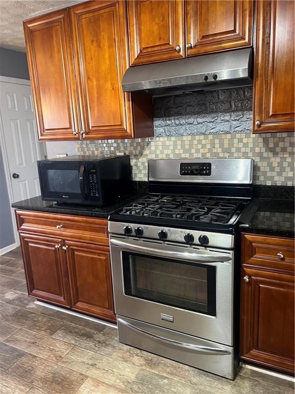 kitchen featuring tasteful backsplash, a textured ceiling, black microwave, stainless steel gas range oven, and under cabinet range hood