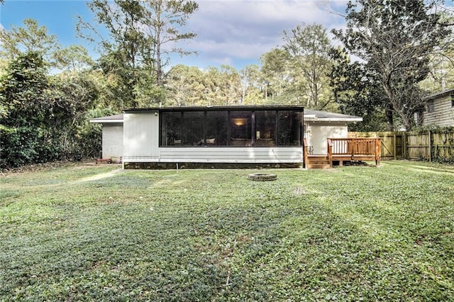 back of property featuring a deck, a lawn, fence, and a sunroom