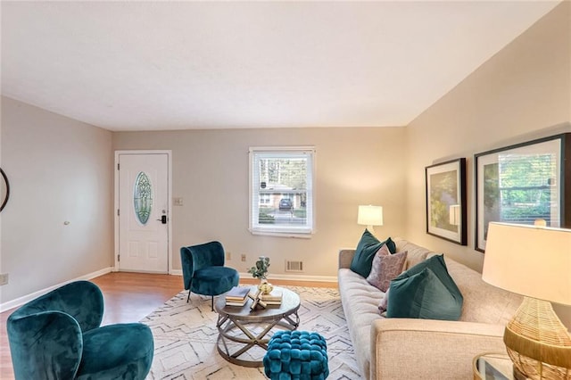 living room featuring visible vents, baseboards, and wood finished floors