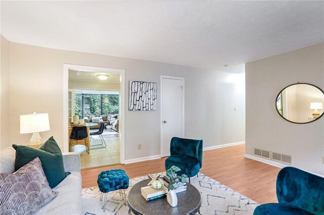 living room featuring baseboards, visible vents, and wood finished floors