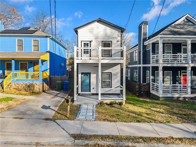 view of front of house with covered porch, a front lawn, and a balcony