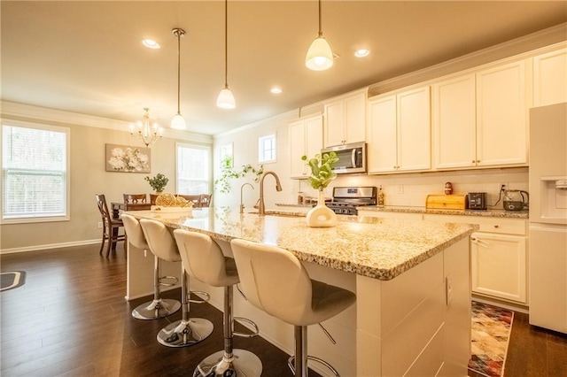 kitchen with hanging light fixtures, appliances with stainless steel finishes, and a kitchen island with sink