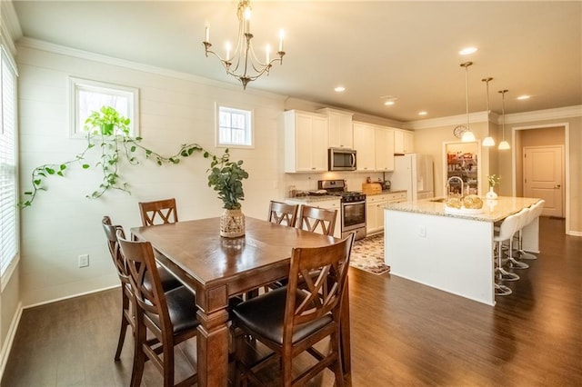 dining area with ornamental molding, dark hardwood / wood-style floors, sink, and an inviting chandelier