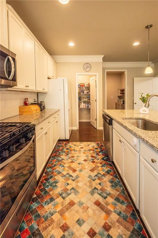 kitchen with light stone countertops, white cabinetry, appliances with stainless steel finishes, and hanging light fixtures