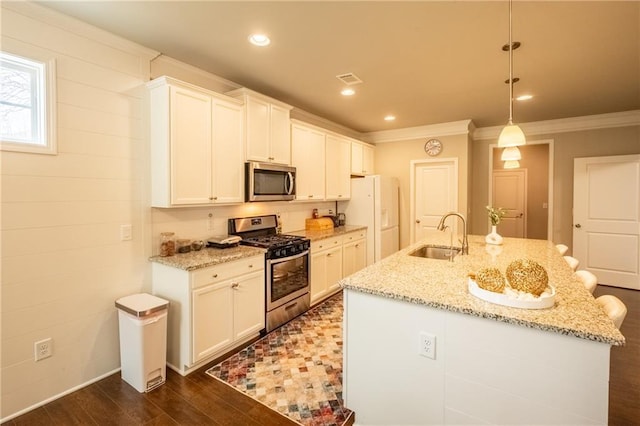 kitchen featuring pendant lighting, stainless steel appliances, light stone countertops, and a kitchen island with sink