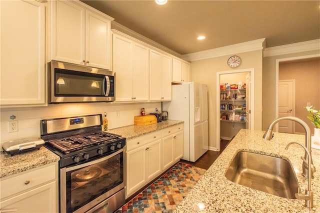 kitchen featuring sink, white cabinetry, crown molding, stainless steel appliances, and light stone countertops