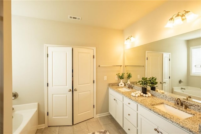 bathroom with vanity, a bath, and tile patterned floors