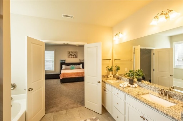 bathroom featuring vanity, a bath, and tile patterned flooring