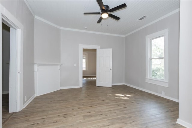 empty room featuring ceiling fan, crown molding, wood-type flooring, and a healthy amount of sunlight