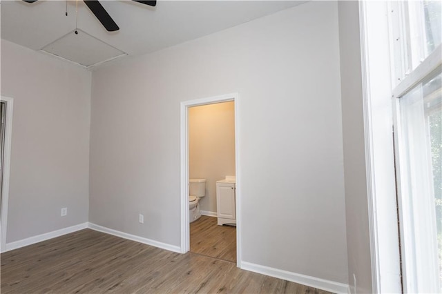 unfurnished bedroom featuring ensuite bathroom and hardwood / wood-style floors