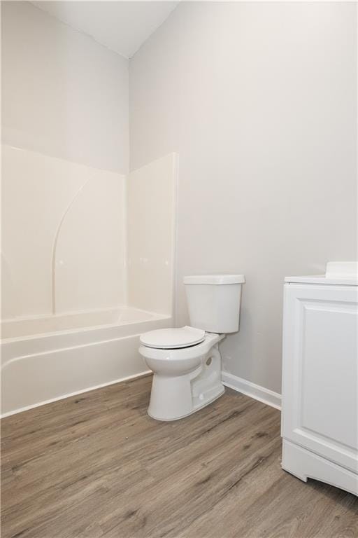 bathroom with wood-type flooring, shower / washtub combination, toilet, and vaulted ceiling