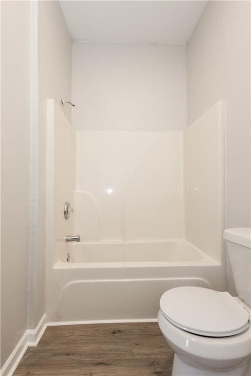 bathroom with hardwood / wood-style flooring, toilet, and bathing tub / shower combination